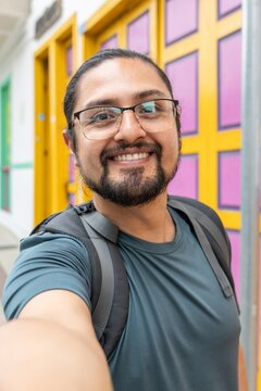 Happy Man with Glasses Taking Selfie by Colorful Door