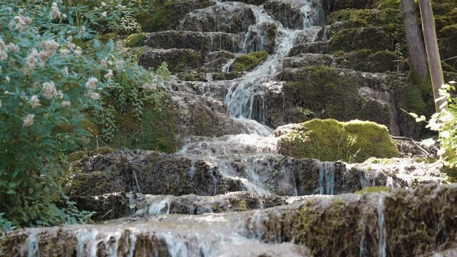 Scenic view of Bigar waterfall cascading over mossy tufa rock steps in a dense forest near Kalna, Stara Planina, Serbia. Cinematic pure nature stream footage shot in summer.