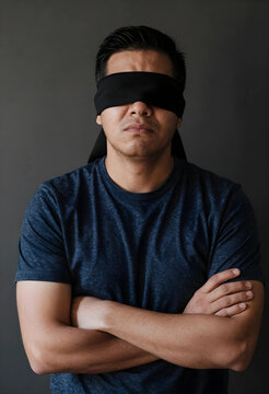 Blindfolded man with crossed arms of uncertainty ignorance injustice and lack of vision or directionless