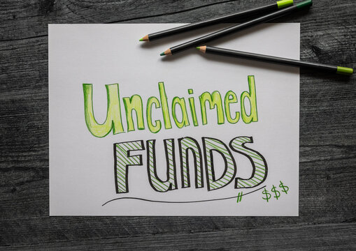 Financial flat lay phot concept Unclaimed Funds with money simples handwritten on white paper.