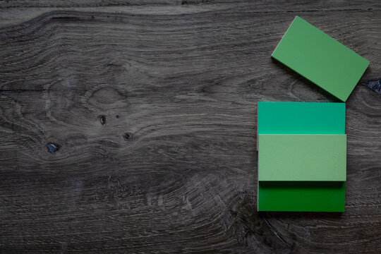 Flat lay background with negative space dark grey wood surface with green wooden tiles.