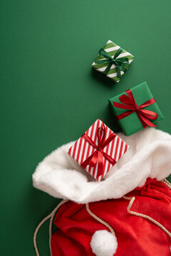 Christmas gifts and Santa present sack with red ribbons for Merry Christmas and Happy New Year on vertical green backdrop