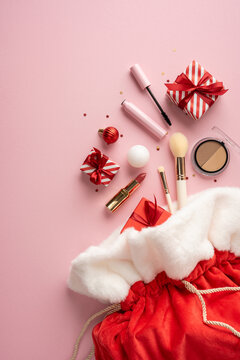 Christmas makeup gift and Santa sack with lipstick brushes ornaments and wrapped present on pink vertical background