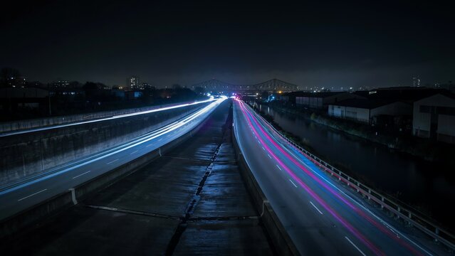 Long exposure highway light trails at night, cinematic blue and purple traffic motion blur, urban freeway transportation background