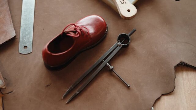 Red Child Shoe with Laces beside Steel Dividers and Ruler on a Brown Pattern Board