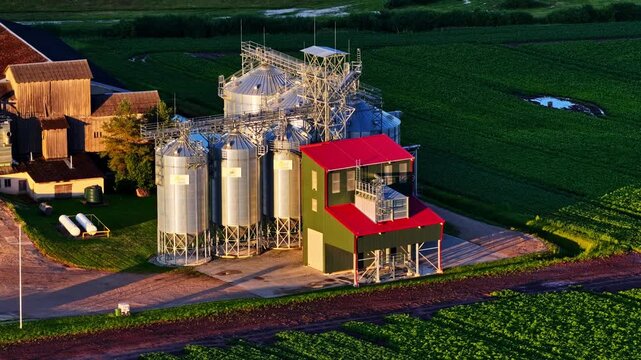 Modern grain elevator and storage bins facility on a farm with green cultivated fields in Michigan, USA