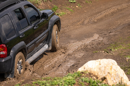 The car drives on a muddy, bad off-road road.