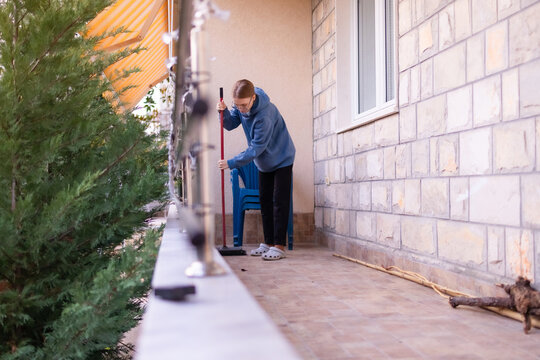 Teenage girl sweeping a balcony at home in Montenegro.