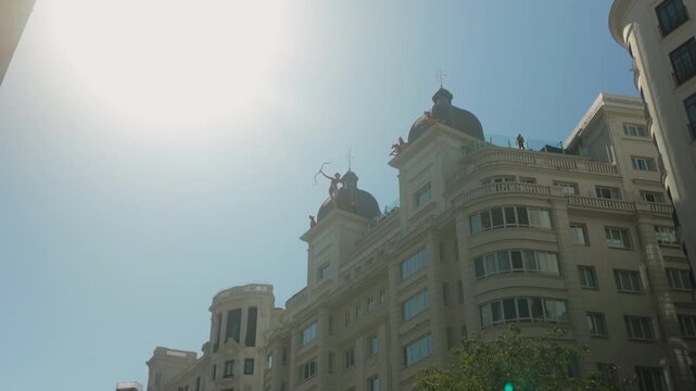 Low angle view of iconic buildings and sculptures on Gran Via in Madrid, Spain. Suitable for travel documentaries, urban lifestyle, and European tourism content.