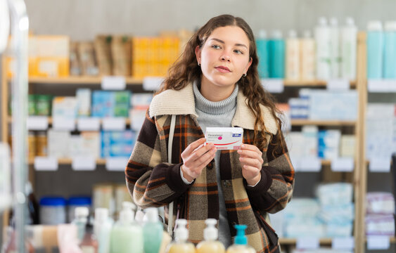 Girl in winter clothes buys paracetamol medicine at a pharmacy
