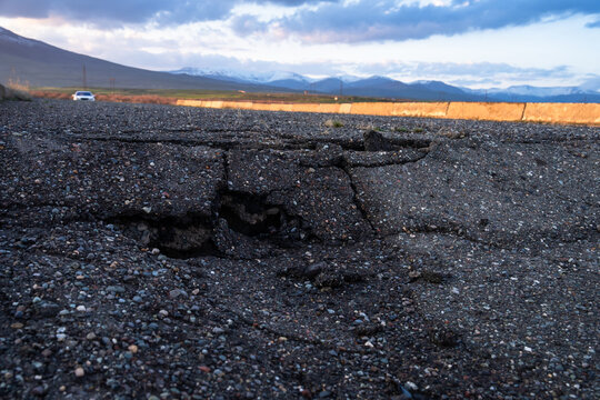 Close-up of a heavily cracked and damaged dark asphalt road