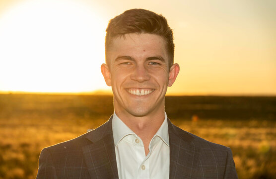 Smiling man in blazer outdoors at sunset