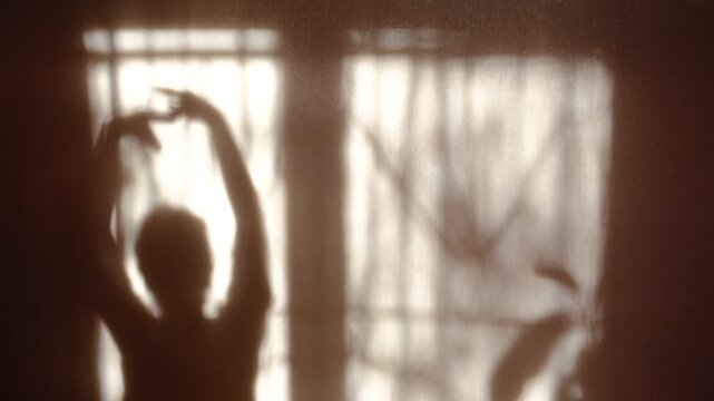 Shadow of happy young dancing lady. Listening music, repetition. Silhouette. She dancing  letting her body move freely. Charm impressed girl. Performance, choreography