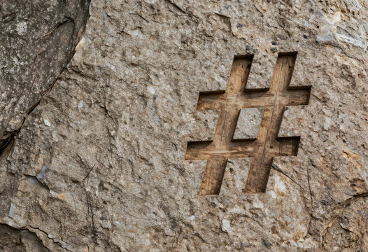 Social media marketing and digital communication, hashtag symbol carved into a rustic stone wall texture