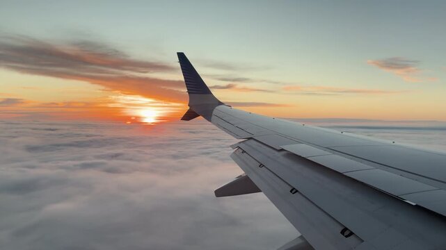 Scenic View of Airplane Wing Through te Window Over Clouds During Golden Sunrise and Early Morning Flight, Travel, Wanderlust. 