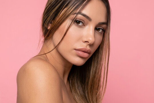 Beauty portrait of a beautiful woman with bare shoulders on a pink background.