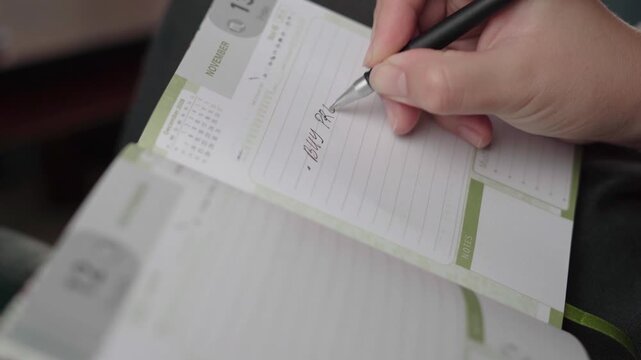 Female hand writes a to-do entry to buy a pregnancy test in a November weekly planner with soft natural light.