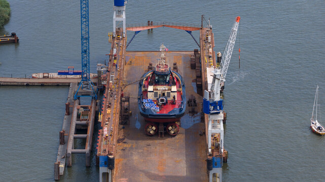 Amsterdam, Noord-Holland, Netherlands - 03 July 2026: Aerial view of Damen Shiprepair Oranjewerf featuring a tugboat undergoing maintenance in a floating dry dock with industrial cranes.