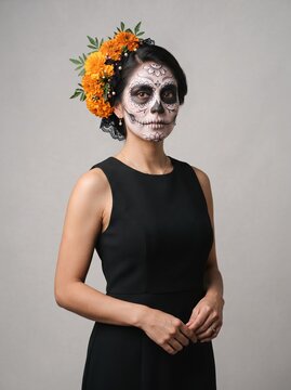 Persona con maquillaje de Catrina y flores de cempas&uacute;chil para el D&iacute;a de Muertos, retrato con vestido negro sobre fondo neutro
