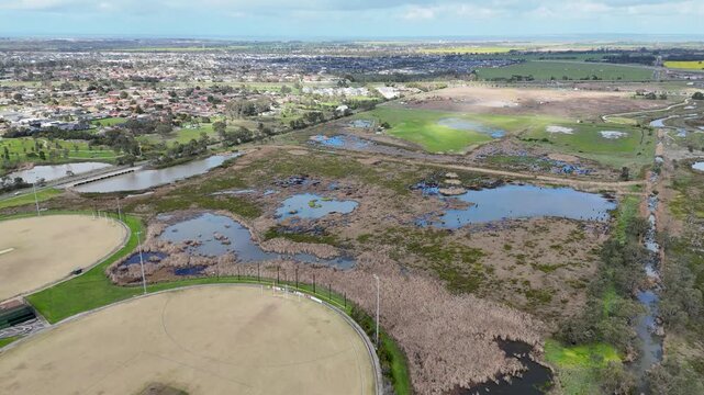 Aerial high-angle of sports ovals, wetland retention basins, bordering residential suburbs in Werribee, Melbourne, Australia. Environmental Conservation Zone&nbsp;as an urban ecological buffer.