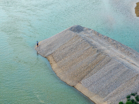 Crna Bara, Serbia - 17 August 2026: Aerial view of a person standing on a gravel bank in the Drina river, surrounded by flowing water.