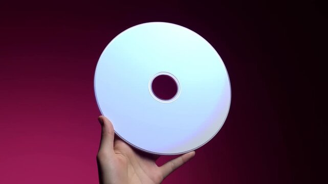 Hand Holding Blank Optical Disc Against Red Background in Centered CloseUp View