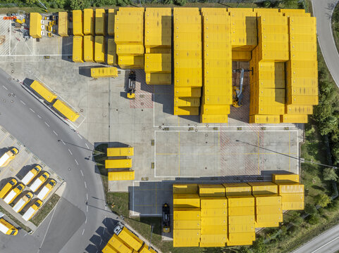 Aschheim, Bavaria, Germany - 20 July 2026: Aerial view of DHL Paketzentrum Aschheim showing rows of yellow shipping containers and logistics trucks.