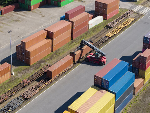 Dabrowa Gornicza, Poland - 09 August 2026: Aerial view of Metrans container terminal with a reach stacker loading shipping containers onto a freight train.