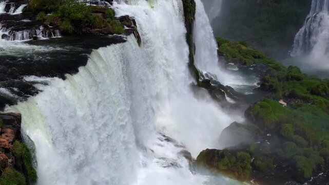 Aerial view of the powerful waterfalls cascading over lush green cliffs in the rainforest