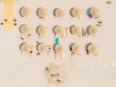 Sarande, Vlore County, Albania - 30 May 2026: Aerial view of Kroreza Beach with rows of straw umbrellas and sun loungers on the sand, with people relaxing.