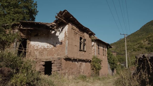 Camera moving forward towards an old abandoned traditional mud brick house with a broken roof in Topli Do village, Stara Planina, Serbia. Cinematic shot of authentic Balkan heritage.