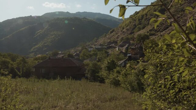 Panoramic view of old traditional houses in Topli Do village nestled in a lush mountain valley on Stara Planina, Serbia. Scenic rural Balkan landscape shot during sunny afternoon.