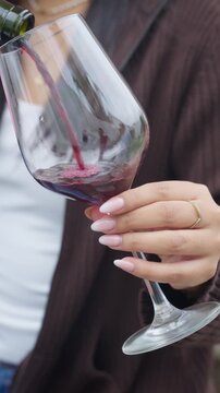 Elegant woman pouring red wine into glass