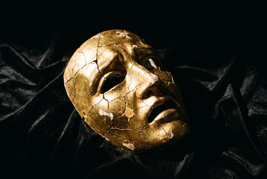 Cracked Golden Theater Mask on Black Velvet with Dramatic Lighting