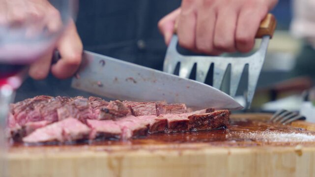 Professional chef slicing grilled beef steak on a wooden board