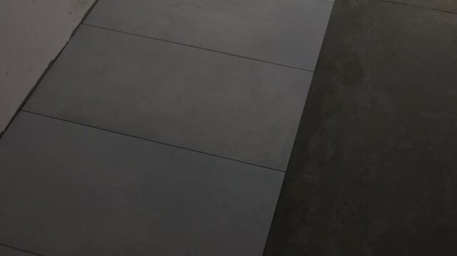 New floor tiles installed beside unfinished concrete floor