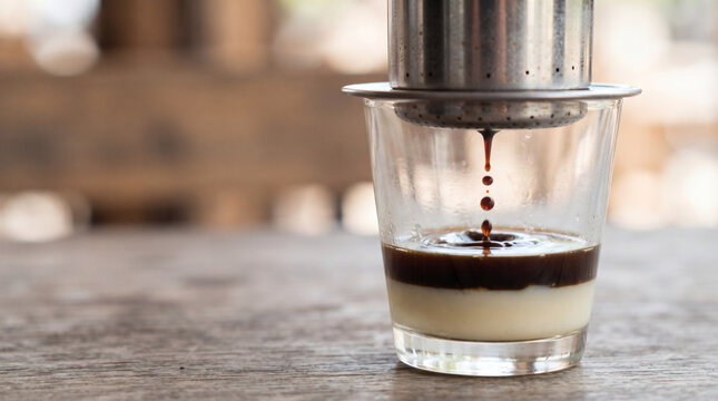 Vietnamese drip coffee dripping into glass with condensed milk