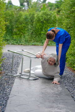 Caregiver nurse senior woman fall walker injury assistance, outdoor walkway accident in garden, anxious patient receiving support and first aid after trip and fall