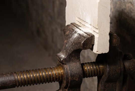 Bench vice holding wood in a workshop close up with industrial metal texture