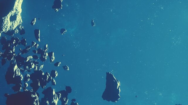 Rocks and asteroids drift in space with a blue background filled with stars. The image captures the vastness of the asteroid belt in an area of the galaxy.