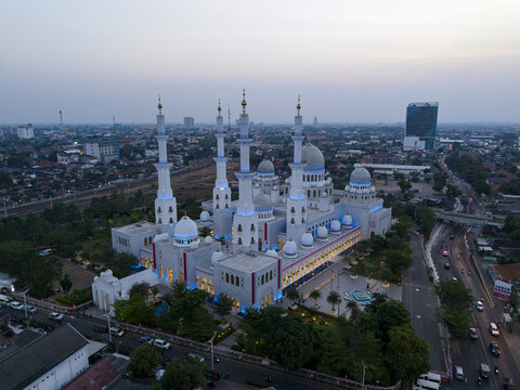 Aerial view of Sheikh Zayed Grand Mosque Surakarta with its white domes and minarets illuminated at dusk, surrounded by the urban landscape of Kecamatan Banjarsari, Jawa Tengah, Indonesia.