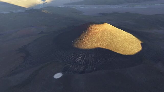 Aerial view of sunlit volcanic cone in La Puna desert