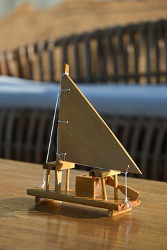 miniature wooden sailboat model on wooden table, handcrafted wooden jangada boat craft at seaside outdoor lounge, rustic nautical decor for tropical event close up