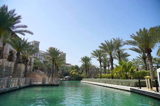 Aerial view of Souk Madinat Jumeirah featuring traditional architecture, palm trees, and a turquoise canal under a clear blue sky in Dubai, Dubai, United Arab Emirates.