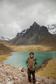 Traveler posing at the lake on the Ausangate mountain trail, Cusco, Peru