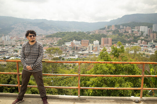 A traveler wearing sunglasses is at a viewpoint overlooking the urban landscape of Medell&iacute;n, Colombia