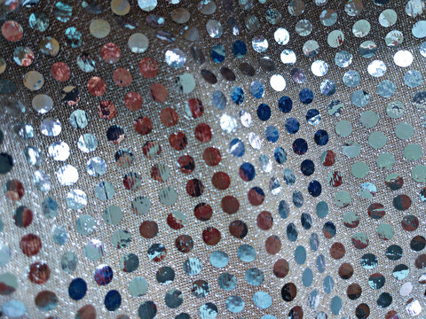 Close up view of shiny sequins on fabric showing various colors and patterns