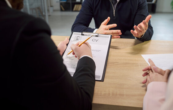 Interview recruiter meets candidate with resume and CV. HR and employer review details as hands gesture, discuss experience and fit for the hiring decision. Clear job hire decision concept.