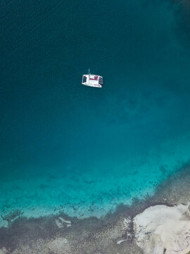 Aerial view of a catamaran sailing in clear turquoise waters near the coastline of Guna Yala Comarca, Panama.
