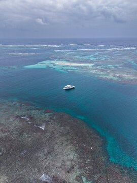 Aerial view of a white yacht anchored in the turquoise waters of a coral reef in Guna Yala Comarca, Panama.
